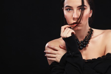 Portrait of beautiful sexy brunnete girl, on black background. Pretty girl model. A brunette woman in a black dress.の写真素材