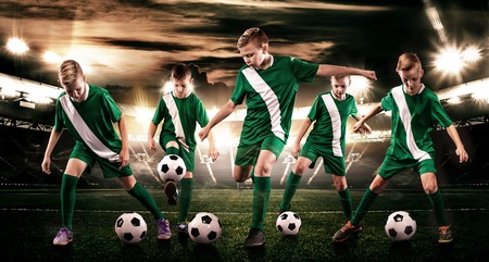 Kids - soccer champions. Boys in football sportswear on stadium with ball. Sport concept with soccer team.の写真素材