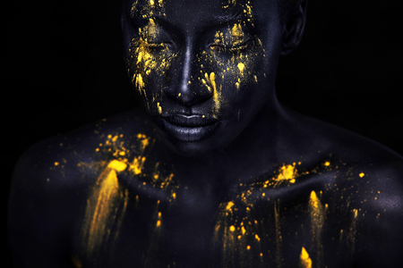 Cheerful young african woman with art fashion makeup. An amazing woman with black makeup and leaking yellow paintの写真素材
