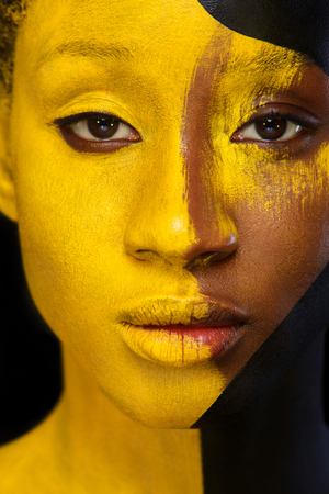 Cheerful young african woman with art fashion makeup. An amazing woman with black and yellow paint makeupの写真素材