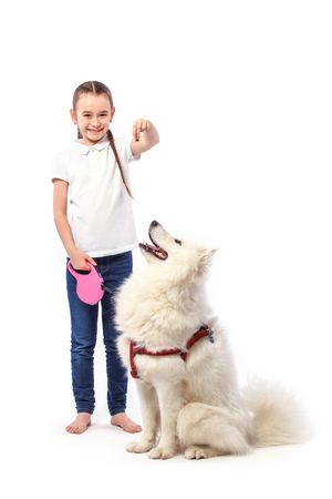 Happy child with white dog. Portrait girl with eating pet. Smilyng Samoyed Laika dog.の写真素材