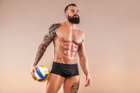 Muscular young fitness sports man with strong fit body on light background. Volleyball concept.の写真素材