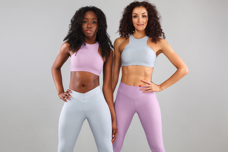 Two fitness women in sportswear isolated over gray background. Sport and fashion concept with copy space.の写真素材
