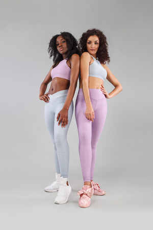 Two fitness women in sportswear isolated over gray background. Sport and fashion concept with copy space.の写真素材