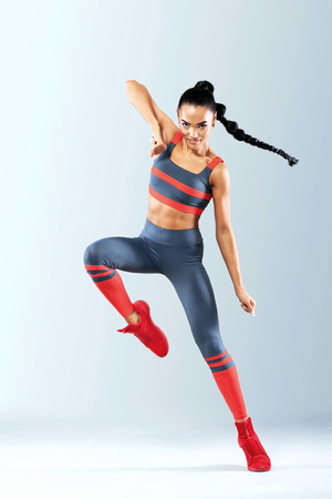Attractive excited fitness girl dancer in sportwear isolated over gray backgroundの写真素材