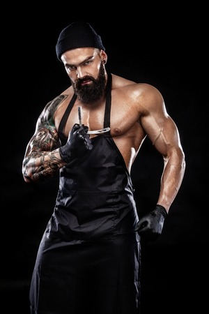 Portrait of bearded barber with a straight razor with tattooe on arm. Barbershop ads concept.の写真素材