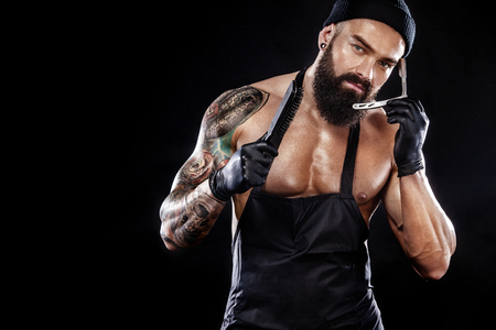Portrait of bearded barber with a straight razor with tattooe on arm. Barbershop ads concept with copy space.の写真素材