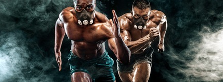 Competition of two strong athletic men sprinters in training mask, running, fitness and sport motivation. Runner concept with copy space. Dynamic movement.の写真素材
