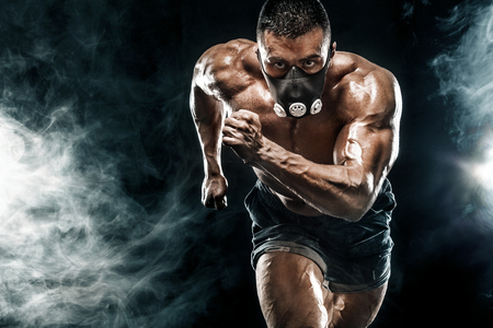 Strong athletic man sprinter in training mask, running, fitness and sport motivation. Runner concept with copy space. Dynamic movement.の写真素材