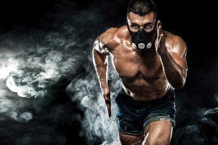 Strong athletic man sprinter in training mask, running, fitness and sport motivation. Runner concept with copy space. Dynamic movement.の写真素材