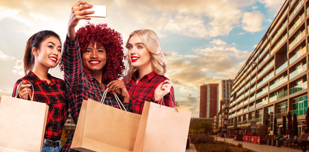 Beautiful young women make shopping in black friday holiday. Girls with bag on lgiht background.の写真素材