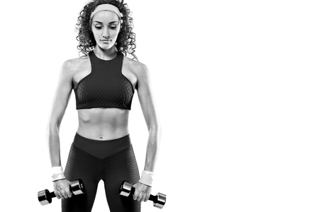 Sporty beautiful woman with dumbbells makes fitness exercising at white background to stay fitの写真素材