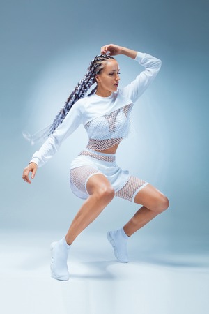 Attractive excited fitness girl dancer in sportwear dance isolated over blue background. Fashion and livestyle concept.の写真素材