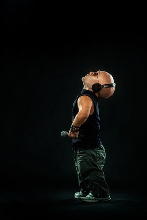 Portrait of stylish midget MC in with headphones and sunglasses posing with microphone.の写真素材