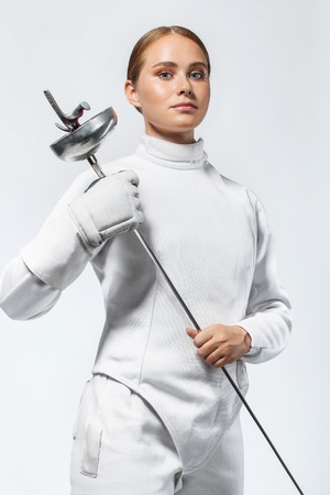 Young fencer athlete wearing fencing costume. holding the sword. Isolated on white background