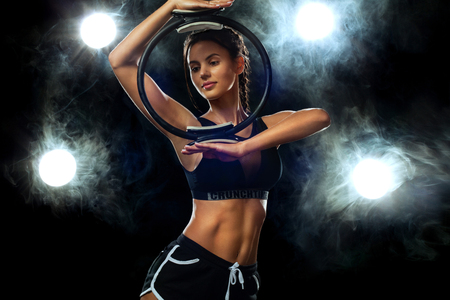 Fitn woman athlete holding gym equipment on black background. Studio shot.の写真素材