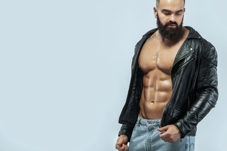 Close-up portrait of a brutal bearded man topless in a leather jacketの写真素材