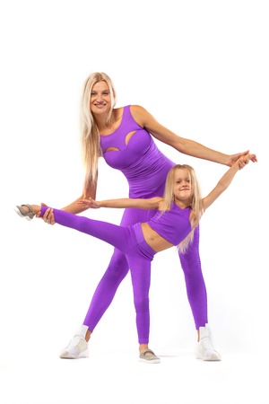 Mothers day concept. Young mother and daughter exercise fitness together indoors. Family look.の写真素材