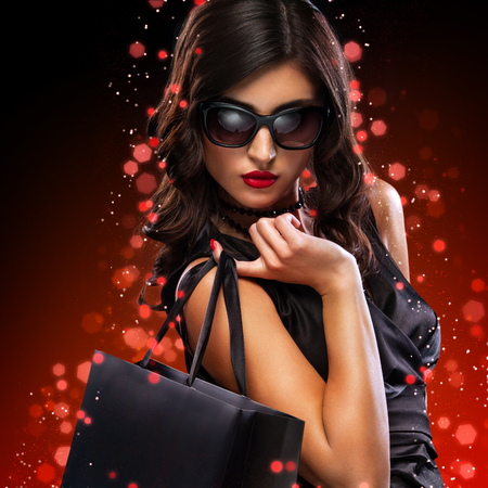 Christmas and Black friday sale concept. Shopping woman holding grey bag isolated on dark background in holidayの写真素材