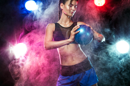 Beautiful fitness woman athlete and bodybuilder with perfect body doing trainging with medicine ball background.の写真素材