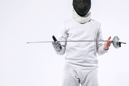 Fencer athlete wearing mask and white fencing costume and holding the sword, . Isolated on white backgroundの写真素材