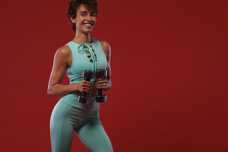 Fitness and sport motivation.. Strong and fit athletic, woman with tattoo posing on red background in sportswear.の写真素材