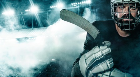 Ice Hockey player in the helmet and gloves on stadium with stick.