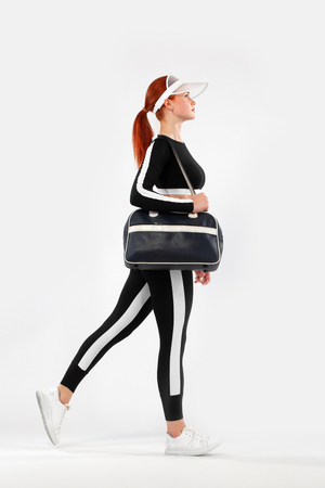 Fitness shopping. Sporty woman with bag running in silhouette on white background.の写真素材