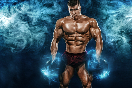 Brutal strong muscular bodybuilder athletic man pumping up muscles with dumbbell on black background. Workout bodybuilding concept. Copy space for sport nutrition ads.の写真素材