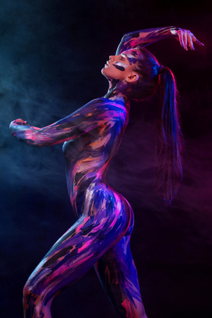 Young woman painted different colors. Inspired dance to music. Bodyart colorful. An amazing woman with art fashion makeup.の写真素材