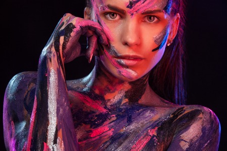 Young woman painted different colors. Inspired dance to music. Body art colorful. An amazing woman with art fashion makeup and bodyart.の写真素材