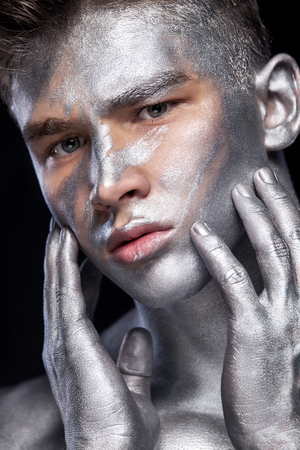 A fashion portrait of man with silver bodyart and face art.の写真素材