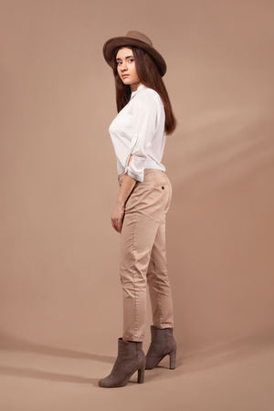 Woman wearing fashion clothes and hat on brown background.の写真素材