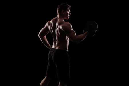 Bodybuilding competitions on the scene. Man sportsmen physique and athlete. Black background with lights.の写真素材