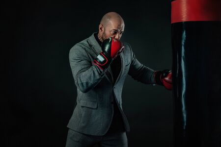 Businessman and sportsman in suit, man boxer in gloves with boxing punching bag. Trainings andの写真素材