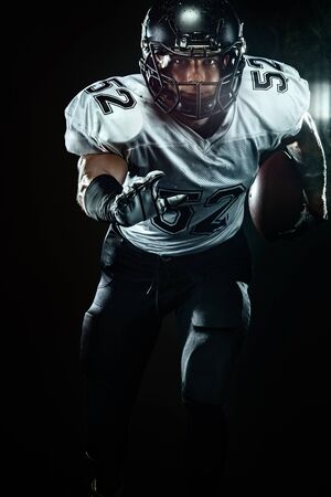 American football sportsman player in helmet on black background with smoke. Sport and motivation wallpaper.の写真素材