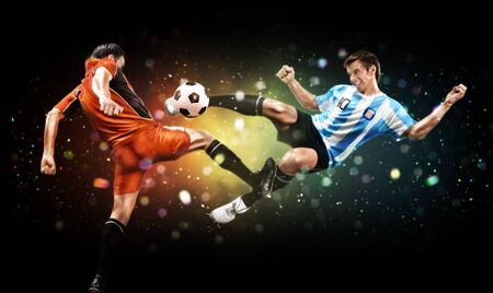 Soccer and sport concept. Two players in action to kick the ball at the football game on dark background with lights and bokehの写真素材