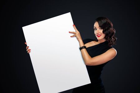 Black friday sale concept with beautiful girl with curly hair. Portrait of young, beautiful and healthy woman with a blank white banner.の写真素材