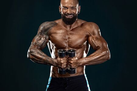 Strong and fit man bodybuilder. Sporty muscular guy with dumbbells. Spot and fitness motivation.の写真素材