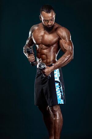 Strong and fit man bodybuilder. Sporty muscular guy with dumbbells. Spot and fitness motivation.の写真素材