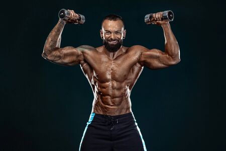 Strong and fit man bodybuilder. Sporty muscular guy with dumbbells. Spot and fitness motivation.の写真素材