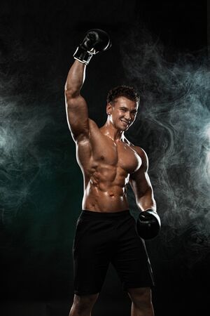 Man, boxer winner and champion after fight in gloves on black background celebrating flawless victory. Fitness and boxing concept. Individual sports recreation.の写真素材