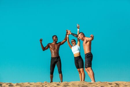 Group of three sportsmens women and men, fit athletes runners after training on sky background. Healthy lifestyle and sport. Friends in black and white sportswear on workout exercise. Fitness concept.の写真素材
