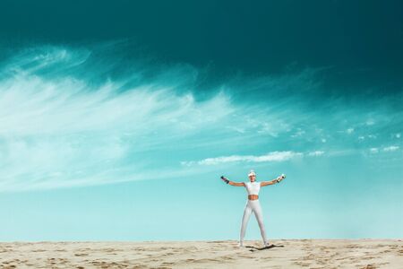 Sporty and fit woman athlete doing training with dumbbells on the sky background. The concept of a healthy lifestyle and sport. Individual sports recreation.の写真素材