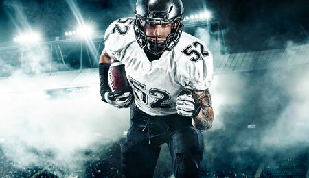 American football player. Sportsman with ball in helmet on stadium in action. Sport wallpaper. Team sports.の写真素材