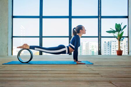 Yoga asana Indoor before a large panoramic window. Sports recreation. Beautiful young woman in yoga pose. Individual sports.の写真素材