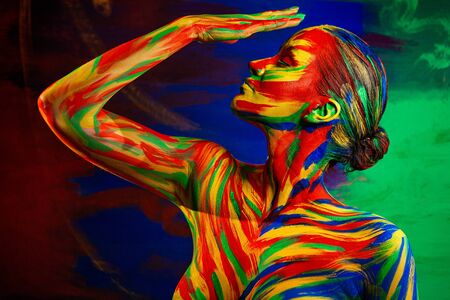 Color art face of woman for inspiration. Abstract portrait of the bright beautiful girl with colorful make-up and body art.の写真素材
