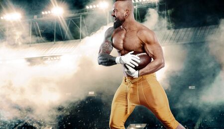 American football player. Sportsman with ball on stadium in action. Sport wallpaper. Team sports.の写真素材