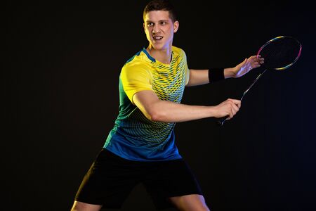Badminton player in sportswear with racket and shuttlecock on black background.の写真素材