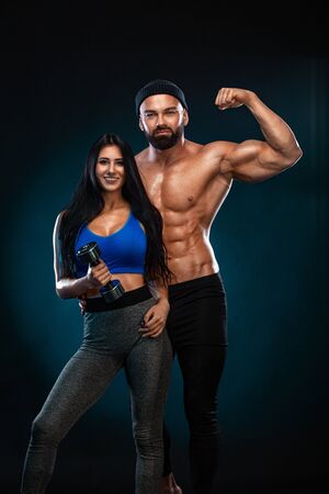 Athletic couple. Man and fit woman with sports equipment on dark background.の写真素材